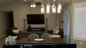 A modern living room with a marble dining table, a flat-screen TV, and a ceiling fan.