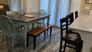 A dining area with a wooden table and chairs, a bench, and a kitchen island with a countertop.