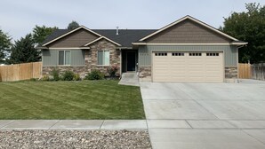A two-story house with a stone facade, a garage, and a well-maintained lawn.