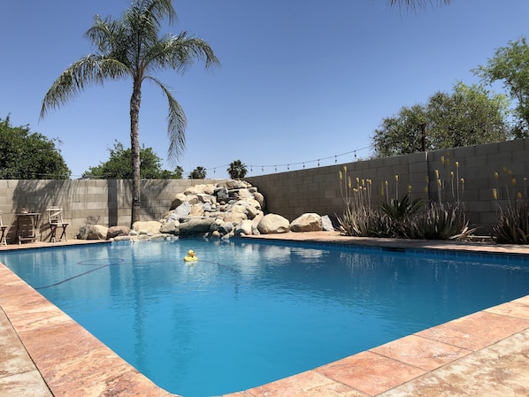 Relax by the rectangular pool surrounded by a tiled deck and lush greenery.