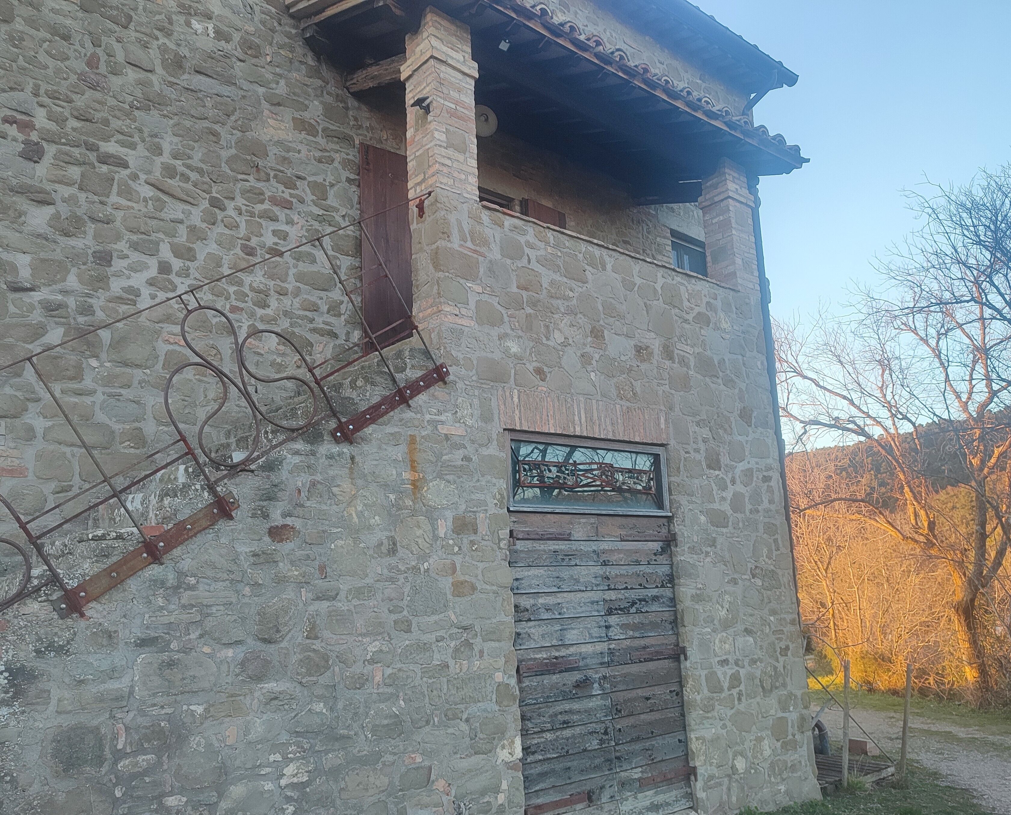 Ein rustikales Steinhaus mit Holztür und Metallgitter.