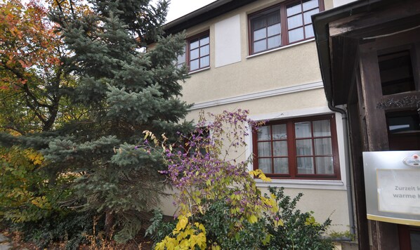 A building with multiple windows and a door, surrounded by various trees and plants. - Parkhotel Schwedt (Schwedt/Oder)