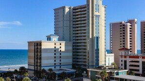 Ein Hochhaus-Hotel mit mehreren Etagen, einem markanten Turm und Blick auf den Strand.