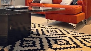 Un salon moderne avec un canapé rouge, une table basse noire et un tapis à motifs.
