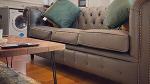 Un salon moderne avec un canapé en cuir, une table basse et une cuisine en arrière-plan.