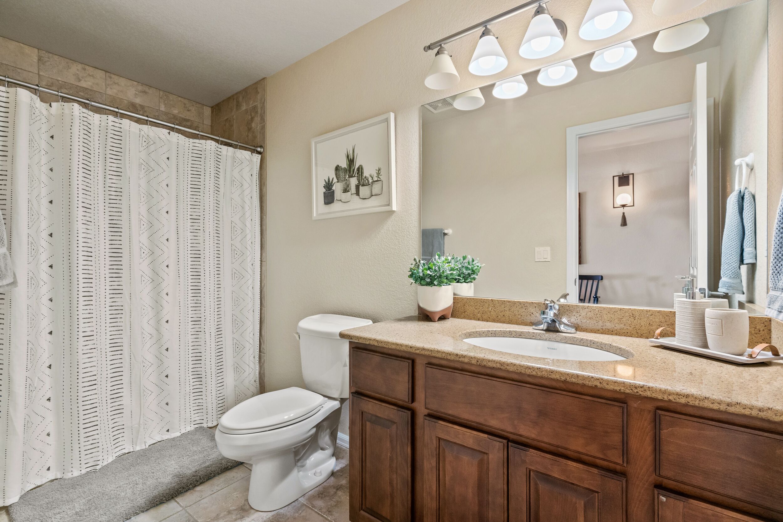 A bathroom with a shower curtain, toilet, sink, and vanity.