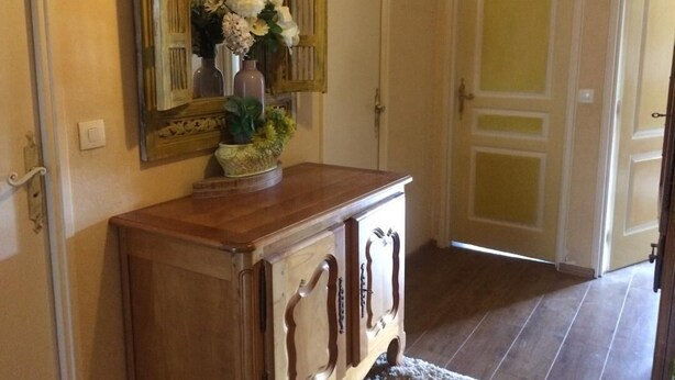 A wooden cabinet with a mirror above it, a vase with flowers, and a door in the background. - SHARED ROOM (Rennes)
