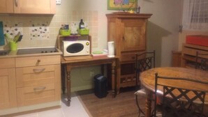 A kitchen with wooden cabinets, a microwave, a small table, and a chair. - SHARED ROOM (Rennes)