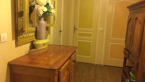A hallway with a wooden dresser, a vase with flowers, and a mirror with an ornate frame. - SHARED ROOM (Rennes)