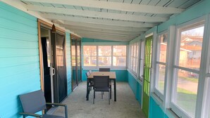 A room with teal walls, a wooden ceiling, a table with chairs, and large windows. - Newly Remodeled Cabin Steps from Sylvan Lake (Rome City)