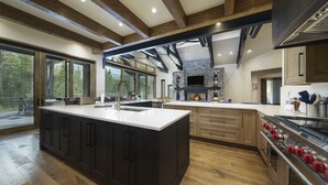 Une cuisine moderne dotée d’un grand îlot central, d’appareils électroménagers intégrés et d’une cheminée en pierre.