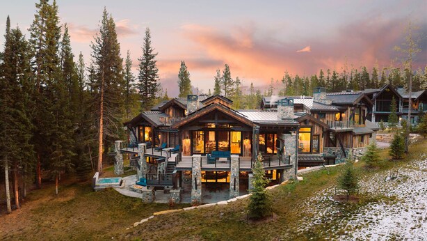 Un complexe hôtelier aménagé dans des chalets en bois, comprenant plusieurs chambres, des terrasses extérieures et une piscine.