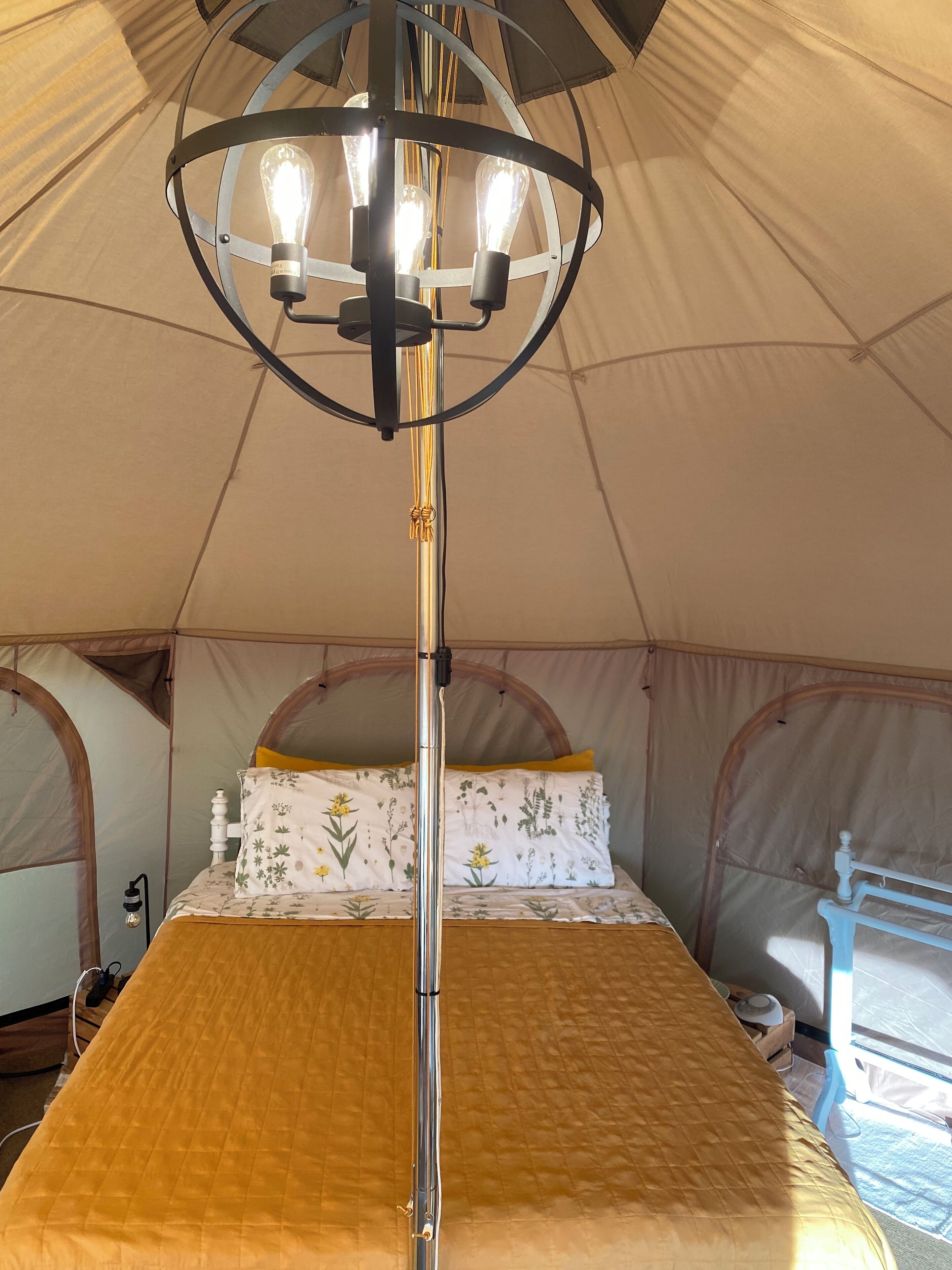 A tent with a bed, a hanging light fixture, and a window.