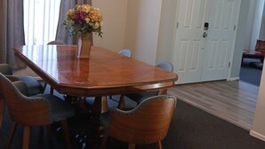 A dining room with a wooden table, six chairs, a chandelier, a vase with flowers, and a door in the background. - LOVE NEST--NEWLY RENOVATED Sleeps 7--CLOSE TO DOWNTOWN, AIRPORT & ATTRACTIONS (Orlando)