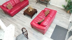 A living room with two red leather sofas, a wooden coffee table, a TV on a stand, and a potted plant. - LOVE NEST--NEWLY RENOVATED Sleeps 7--CLOSE TO DOWNTOWN, AIRPORT & ATTRACTIONS (Orlando)