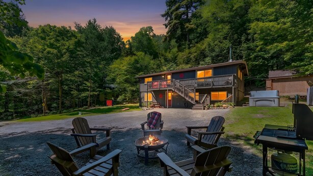 A cabin with a fire pit, outdoor seating, and a staircase leading to a deck.
