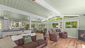 A cabin interior with a dining area, kitchen, and seating space.