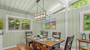 A dining area with a wooden table set for four, surrounded by chairs.