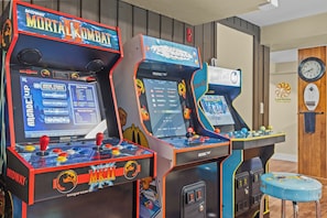 Máquinas de arcade con Mortal Kombat y otros juegos, un reloj y una pared de madera.