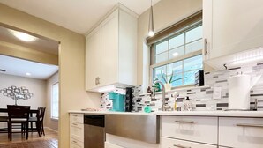 A modern kitchen with white cabinets, a stainless steel dishwasher, and a window above the sink. - Pets Welcome! HOT TUB, Games, Backyard, Free Wine, WiFi, 4 TVs (Richardson)