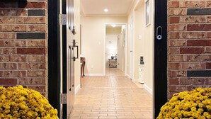 A hotel entrance with a brick facade, a welcome mat, and yellow flowers. - Pets Welcome! HOT TUB, Games, Backyard, Free Wine, WiFi, 4 TVs (Richardson)