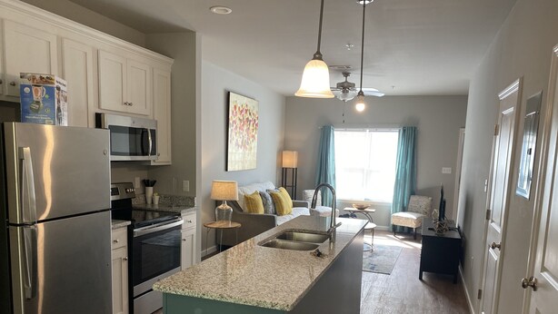 A modern kitchen with stainless steel appliances, a granite countertop island, and a view to the living area. - Valdosta Oasis: 2BR 2.5 BA near VSU and Downtown (Valdosta)