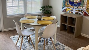 A dining area with a round table, white chairs, yellow placemats, and a patterned rug. - Valdosta Oasis: 2BR 2.5 BA near VSU and Downtown (Valdosta)