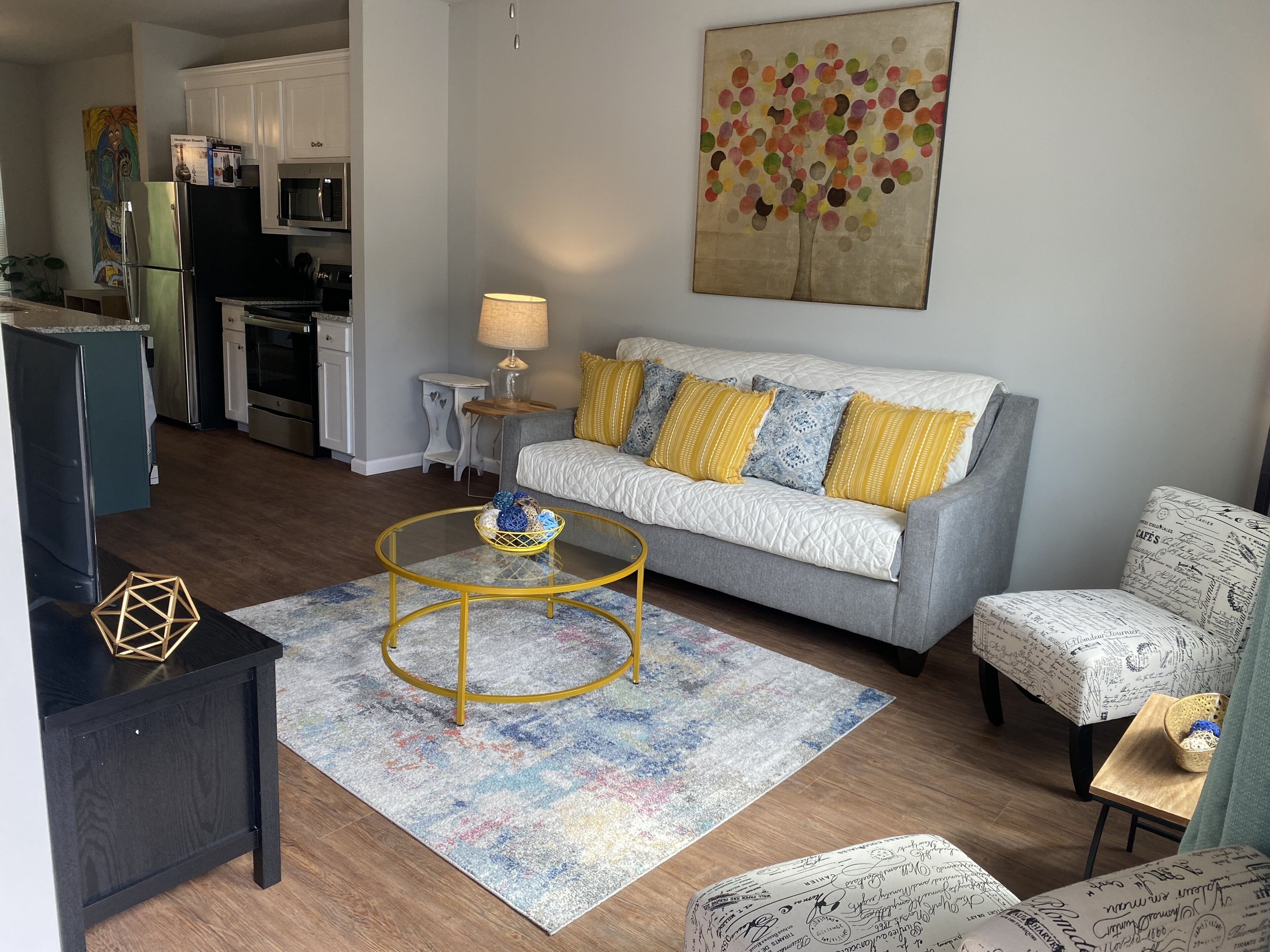 Een moderne woonkamer met een bank, fauteuil, salontafel en een schilderij aan de muur.
