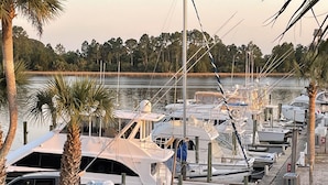 A marina with multiple boats docked, surrounded by trees and a calm body of water. - Carrabelle River Condo  (Carrabelle)