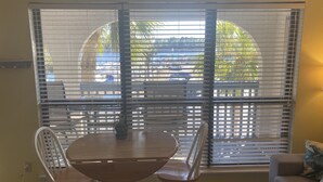 A dining area with a round table and four chairs, a window with blinds, and a wall decorated with fish artwork. - Carrabelle River Condo  (Carrabelle)
