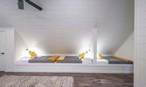 Een slaapkamer met kap en een ingebouwde zithoek, met een patroonrijk vloerkleed.