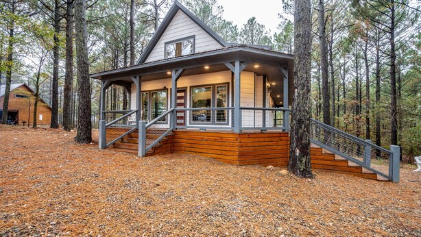 A cabin with a covered porch, wooden steps, and a staircase leading to the entrance.