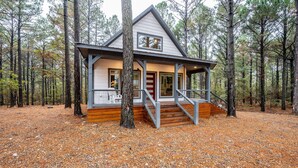 A cabin with a porch, wooden steps, and a view of the surrounding forest.
