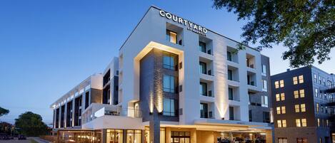 Un hotel Courtyard by Marriott con diseño moderno, amplias ventanas y una entrada bien iluminada.