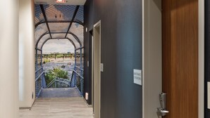 A hallway with a view of a landscaped area through a glass enclosure. - Courtyard by Marriott Richmond Scott’s Addition (Richmond)