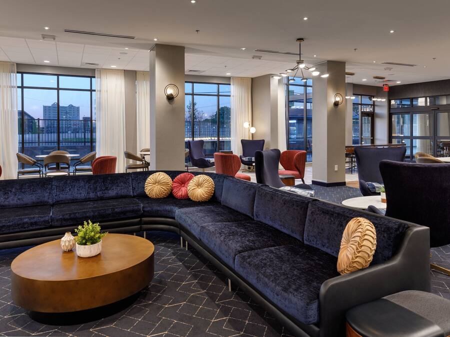 A modern hotel lobby with a large sectional sofa, round coffee table, and various seating options.