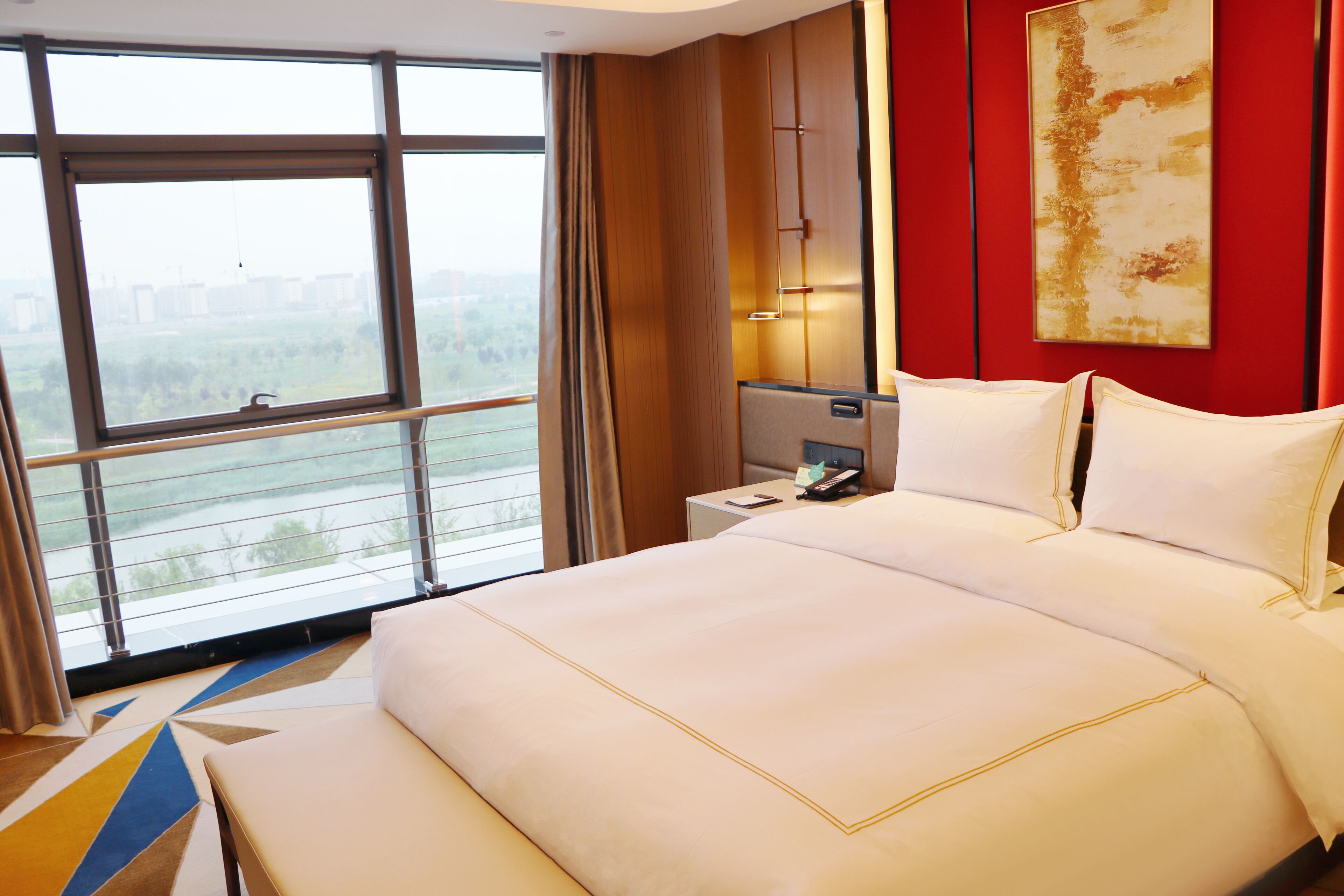Habitación de hotel con una cama grande, una mesita de noche, un escritorio y una ventana con vista a la ciudad.