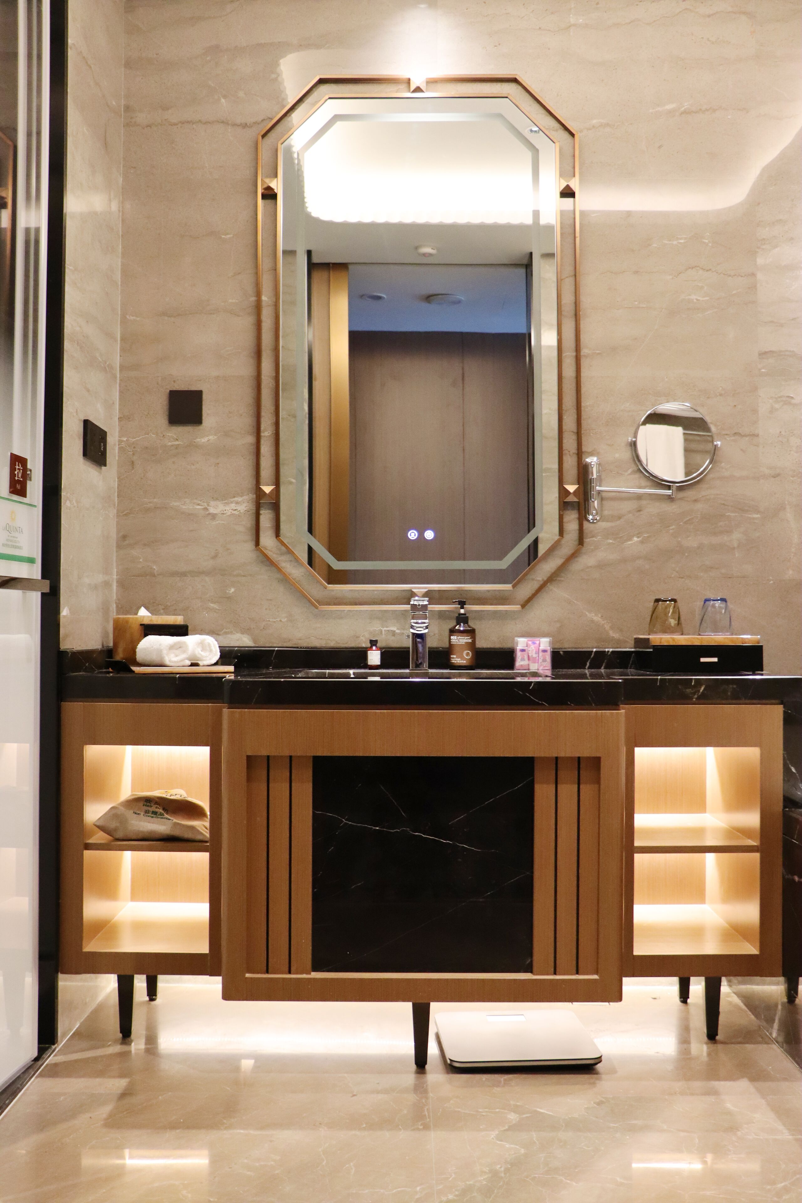 Un baño moderno con un espejo grande, encimera de mármol negro y armarios de madera.