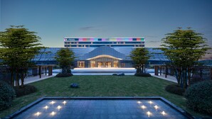 Un hotel moderno con un patio central, una piscina con velas y vistas al mar.