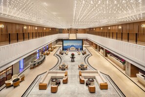 Un hall d’entrée spacieux avec un espace salon central, un grand écran et un design moderne.