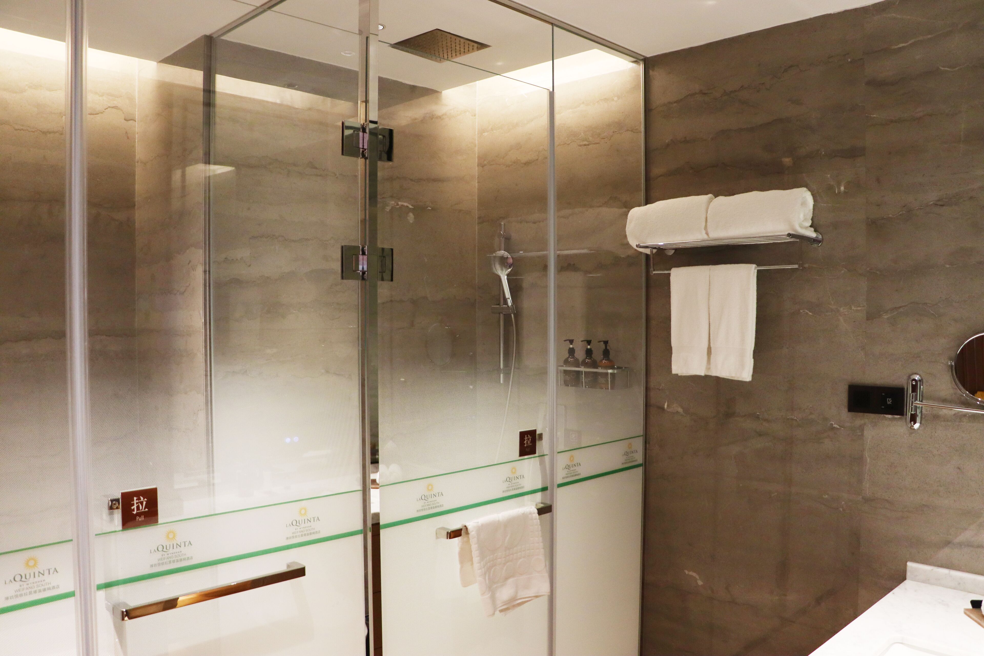 Un baño moderno con ducha envuelta en vidrio, un perchero y un lavabo.
