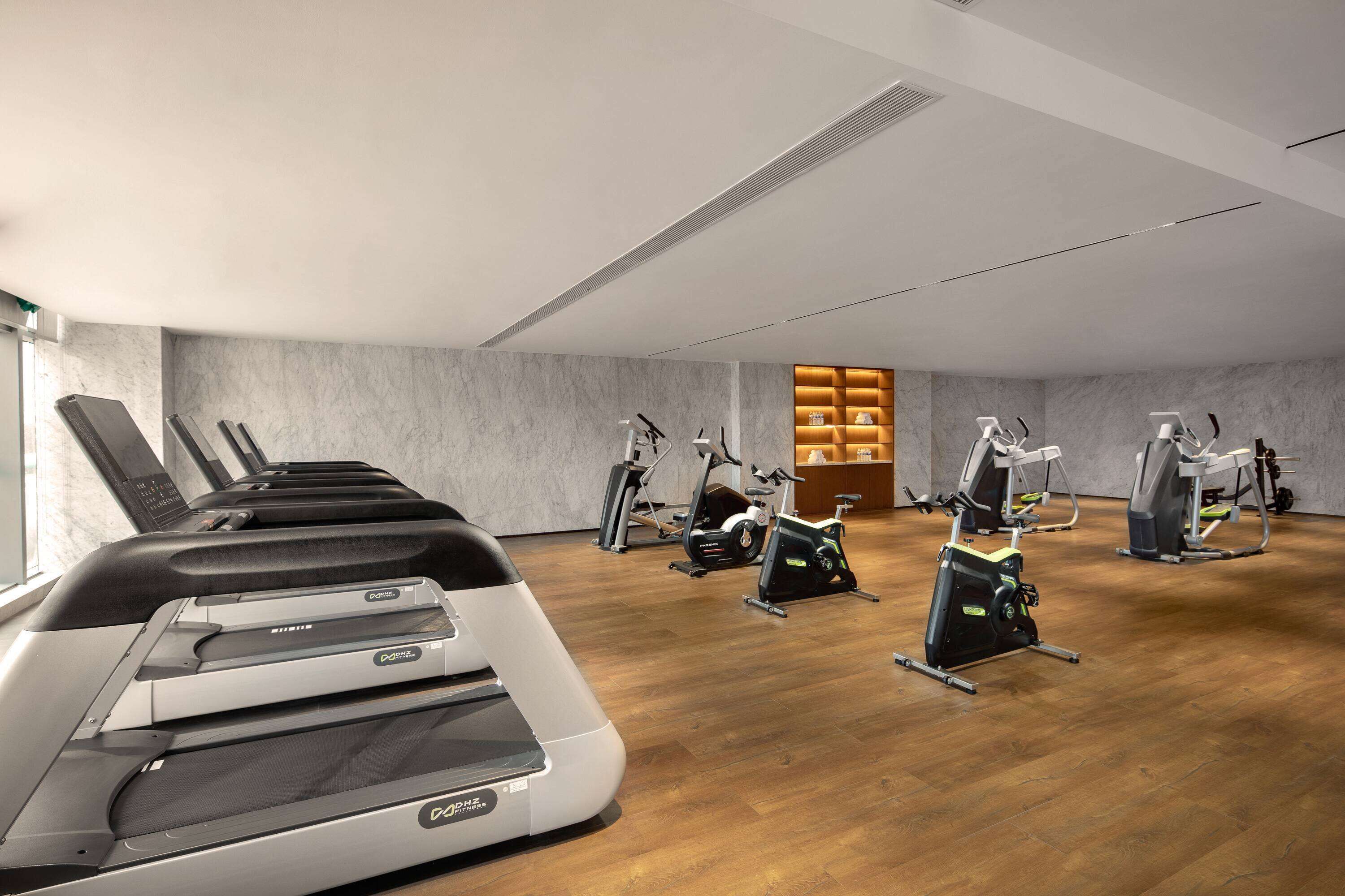 A gym with treadmills, elliptical machines, and stationary bikes.