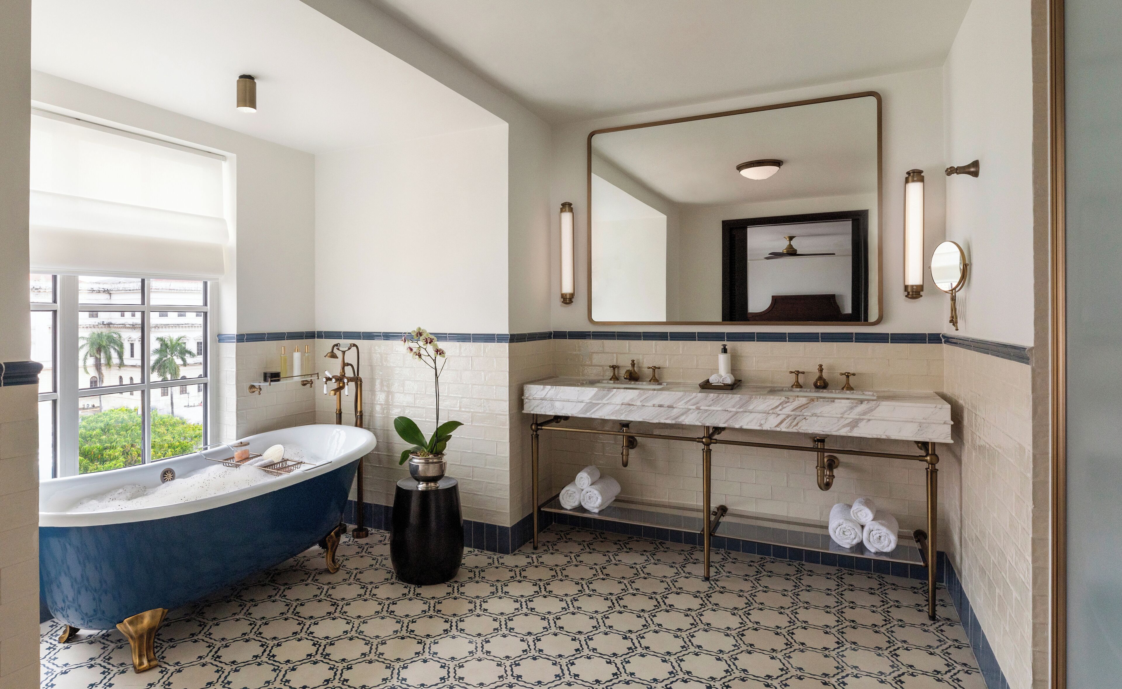 A bathroom with a vintage bathtub, a large mirror, and a marble sink.