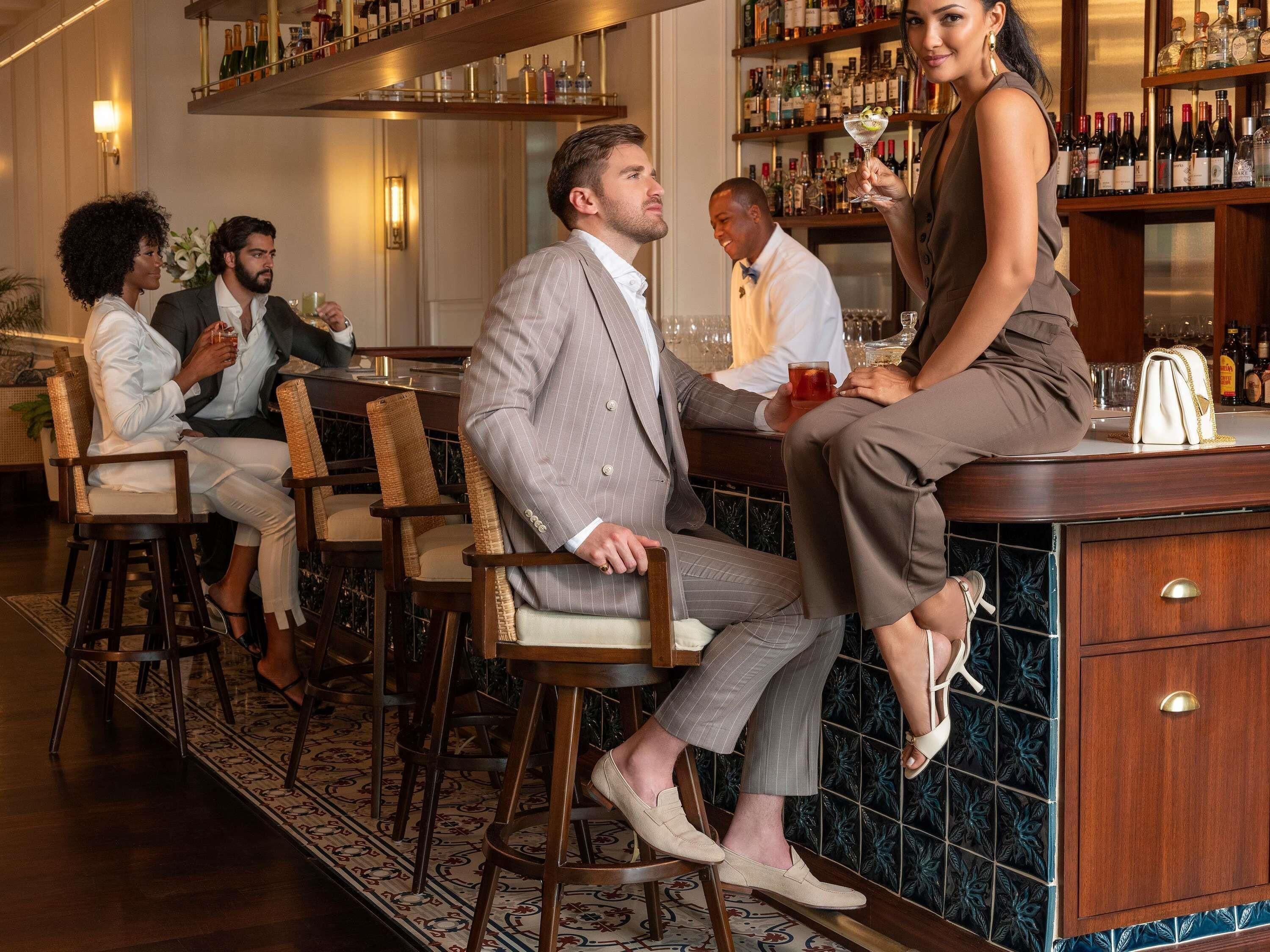 A bar area with wooden chairs, a bar counter, and shelves with bottles.