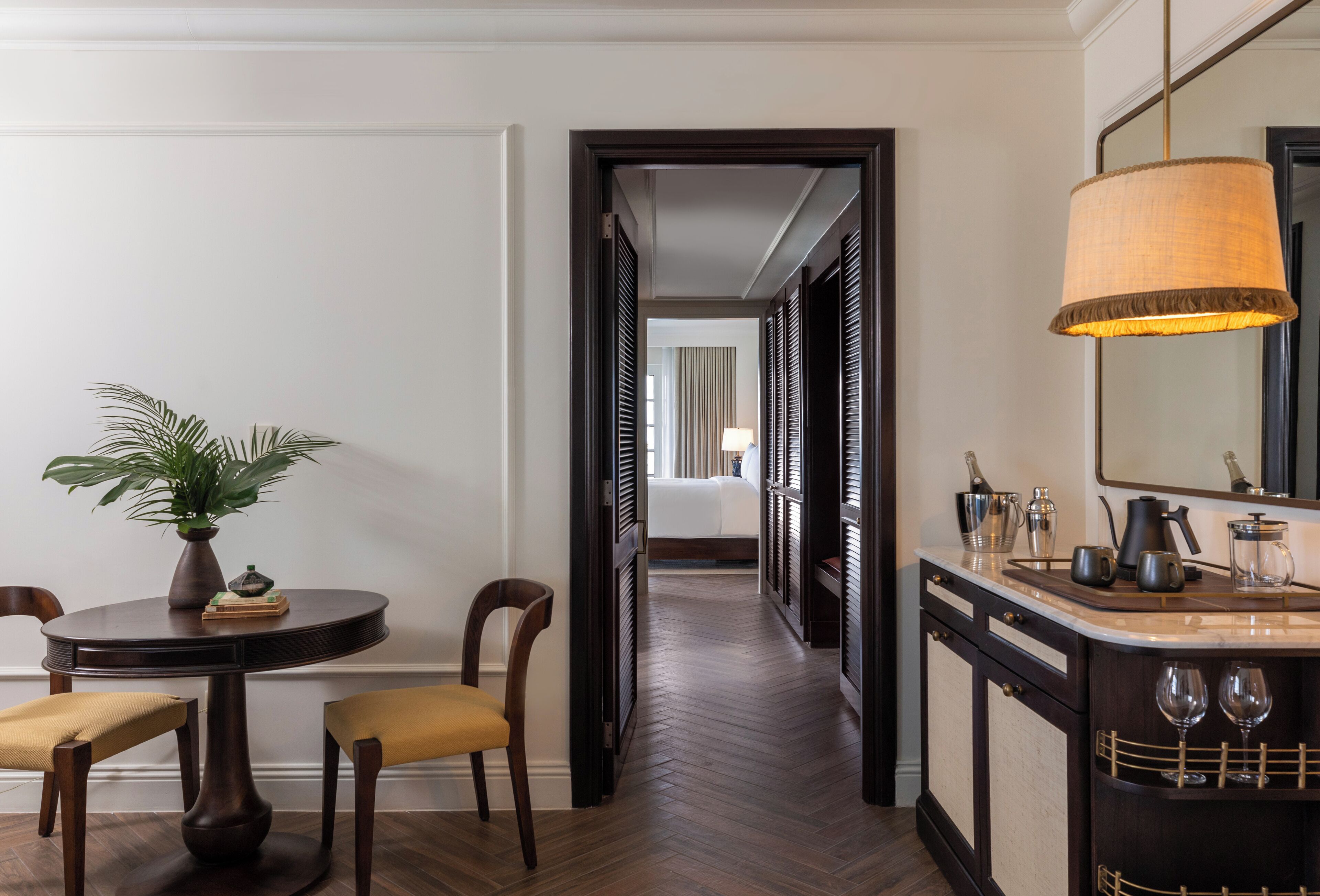 Pasillo de hotel con comedor que incluye una mesa redonda, sillas y una planta en maceta.