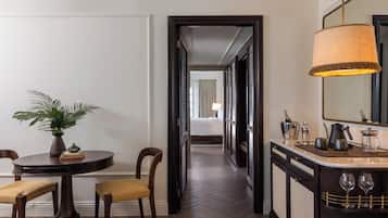 A hotel corridor with a dining area featuring a round table, chairs, and a potted plant.