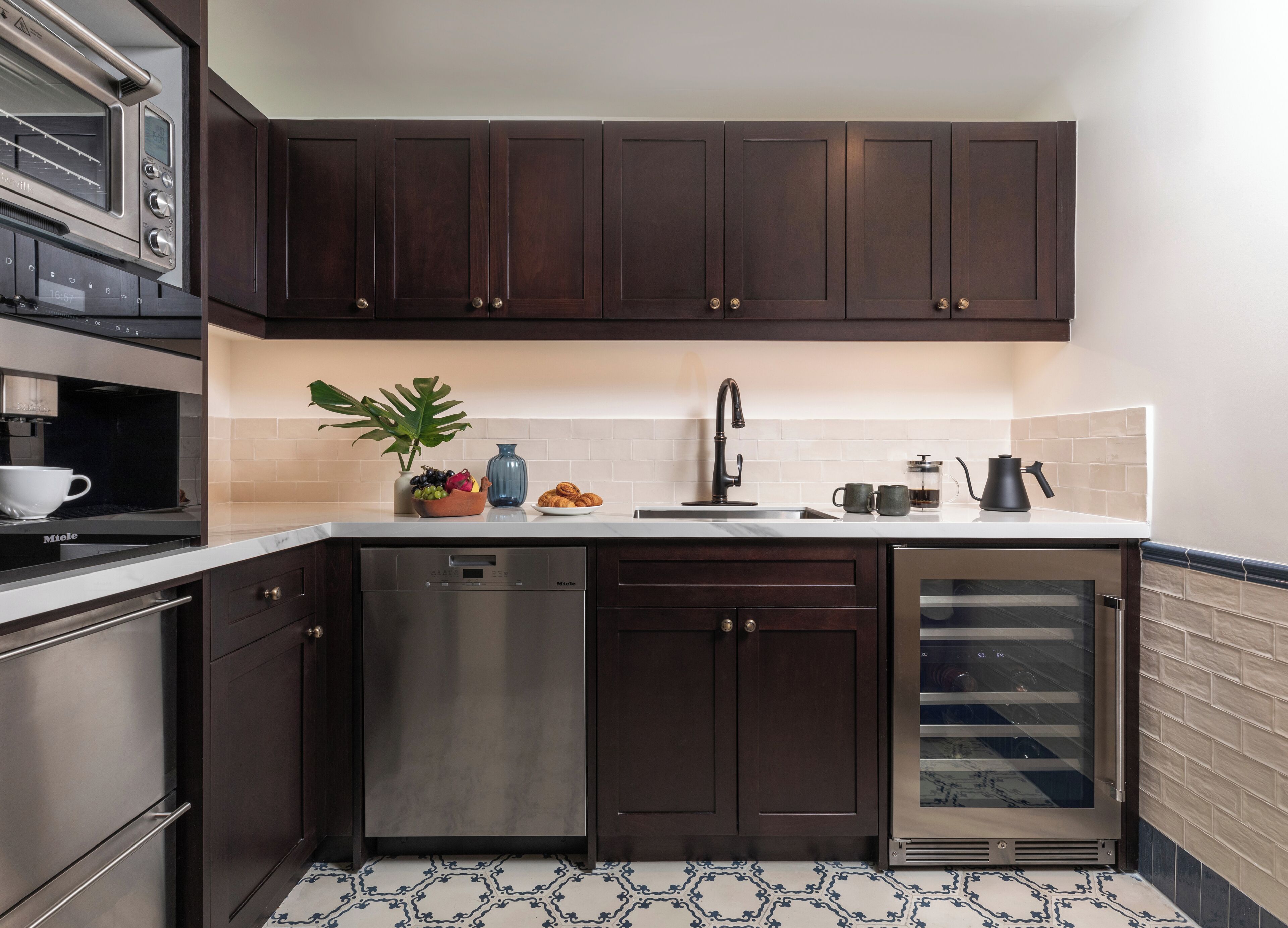 Una cocina moderna con armarios de madera oscura, electrodomésticos de acero inoxidable y salpicadero de azulejos.