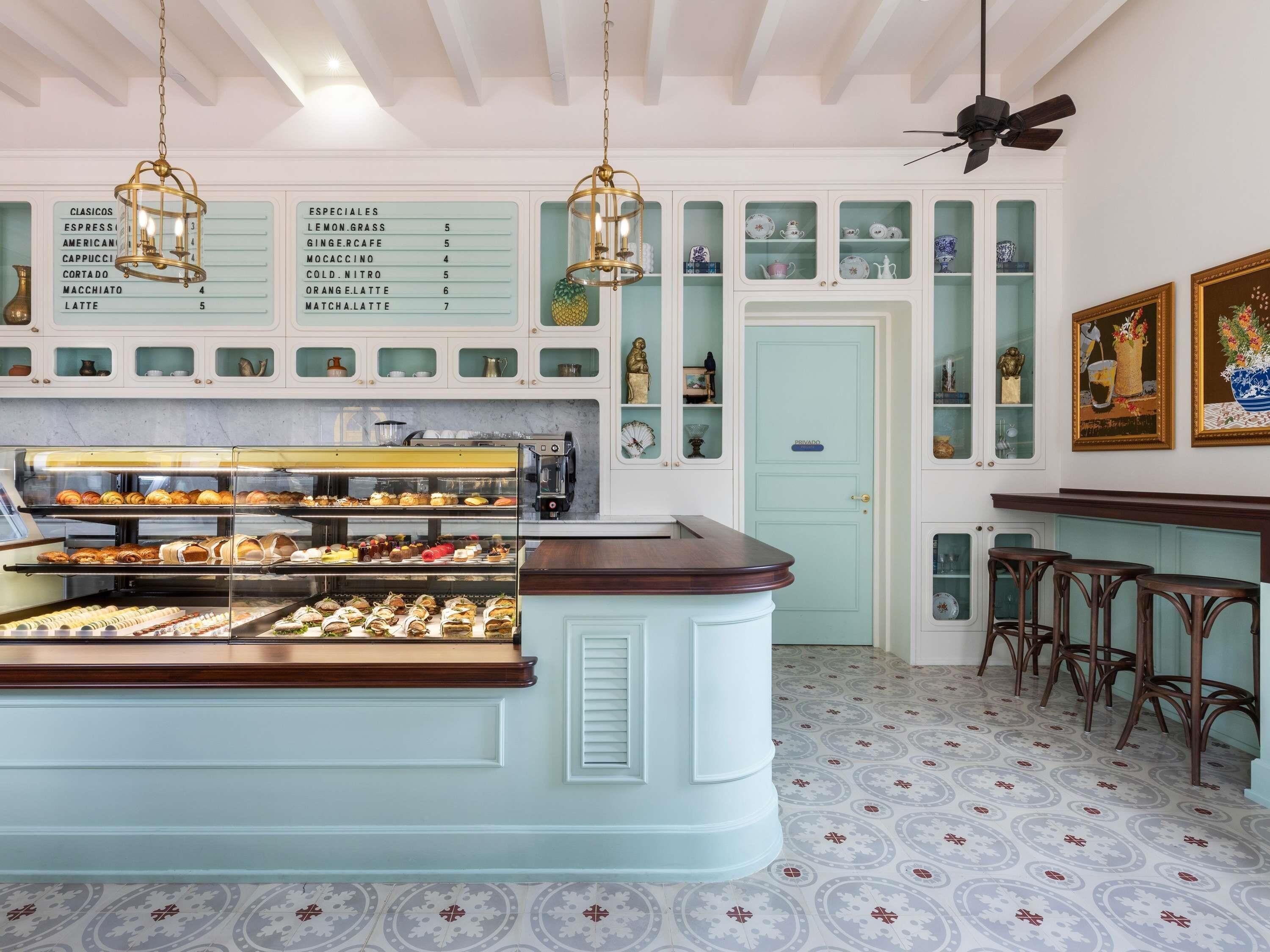 A café with a display case of pastries, a coffee machine, and a menu board listing various coffee drinks.