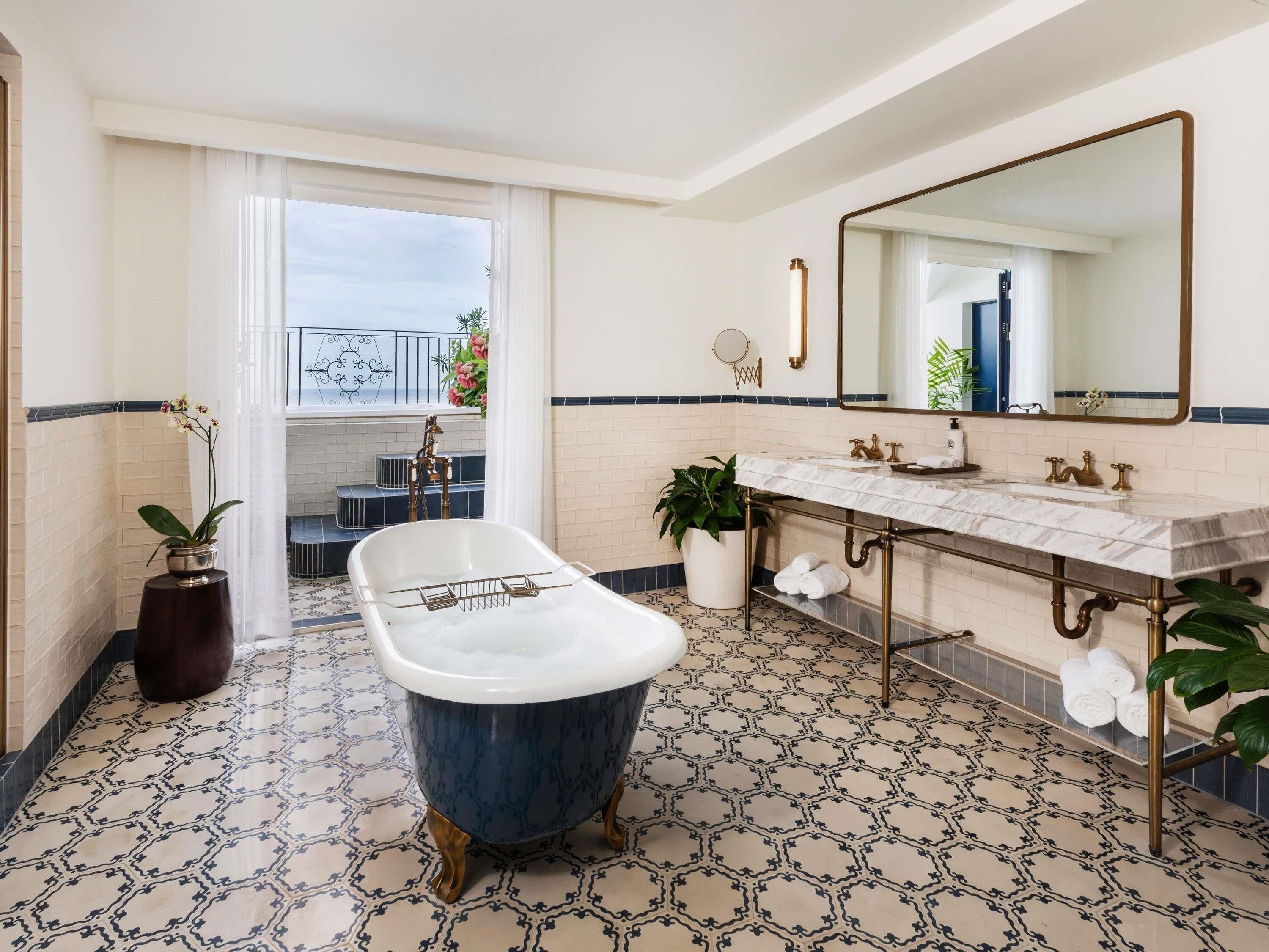 Un baño con una bañera independiente, un espejo grande y un lavamanos doble.