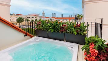 Une piscine sur le toit offrant une vue sur la ville, entourée d’une végétation luxuriante et accessible par un escalier.